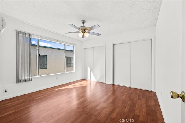 interior space featuring wood-type flooring, two closets, a textured ceiling, and ceiling fan