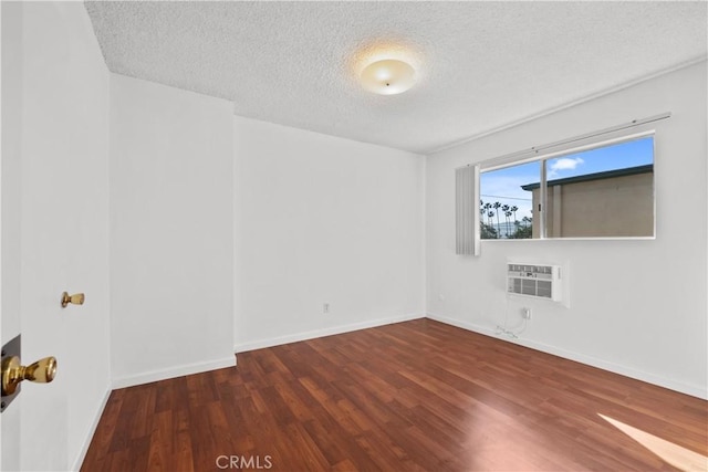 empty room with a wall mounted air conditioner, dark hardwood / wood-style floors, and a textured ceiling