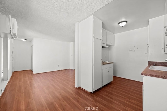 kitchen featuring white cabinetry, wood-type flooring, sink, and a textured ceiling