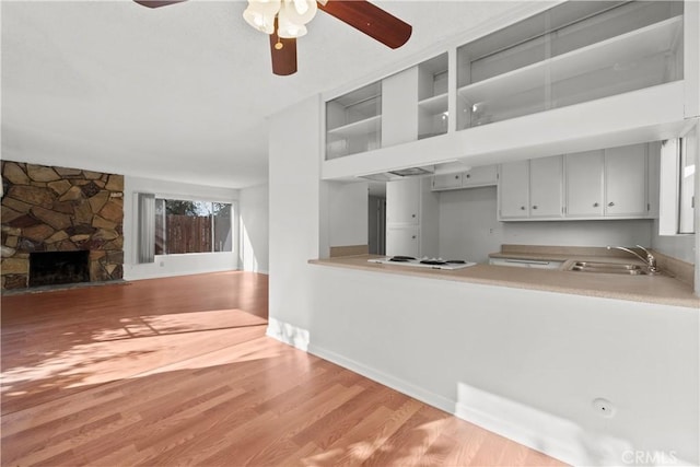 kitchen featuring sink, hardwood / wood-style flooring, a fireplace, kitchen peninsula, and white electric stovetop