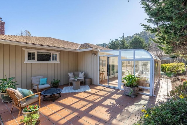 view of patio / terrace with an outdoor fire pit and a sunroom