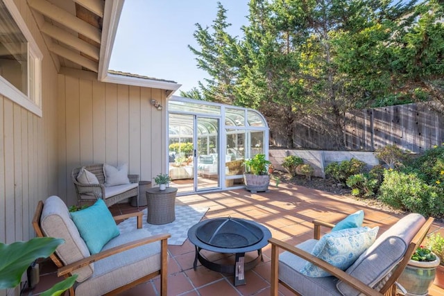 view of patio featuring a sunroom and an outdoor living space with a fire pit