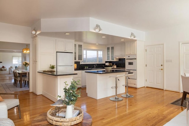 kitchen featuring white cabinetry, white appliances, and light hardwood / wood-style flooring