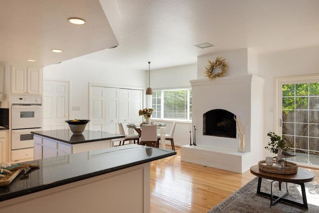 kitchen with a center island, pendant lighting, double oven, and light hardwood / wood-style flooring