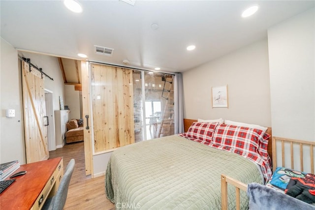 bedroom featuring a barn door and light wood-type flooring