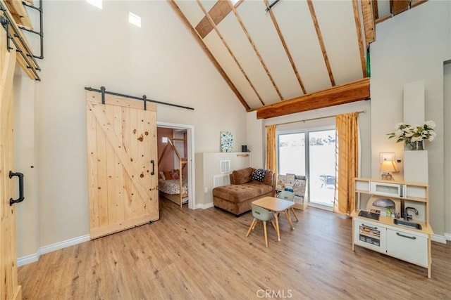 living area with beam ceiling, a barn door, light wood-type flooring, and high vaulted ceiling