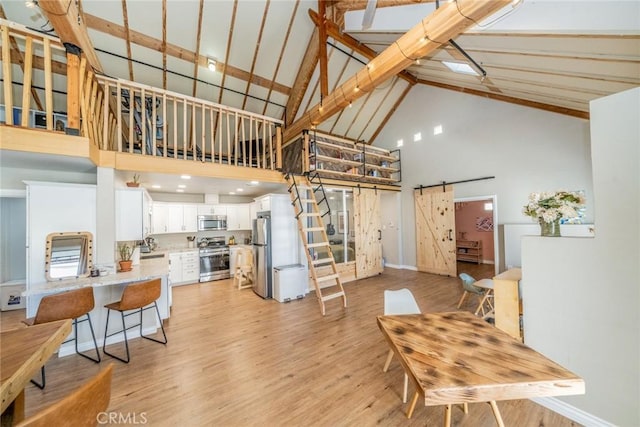 living room with a barn door, light hardwood / wood-style floors, high vaulted ceiling, and beam ceiling