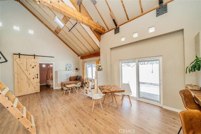 dining room featuring hardwood / wood-style floors, high vaulted ceiling, a barn door, and beamed ceiling