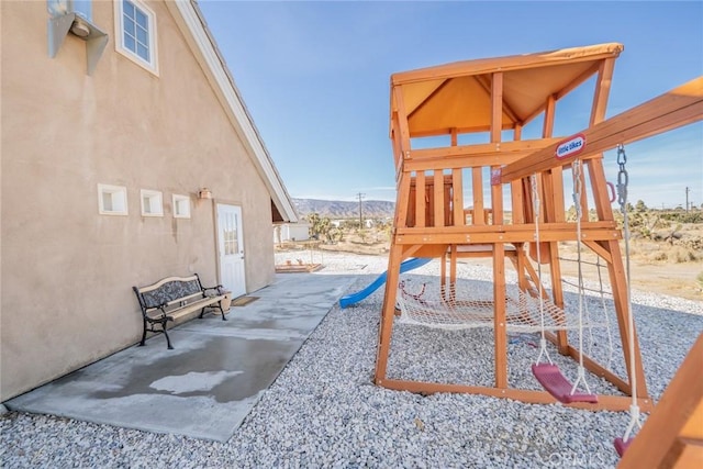 view of jungle gym featuring a mountain view and a patio area