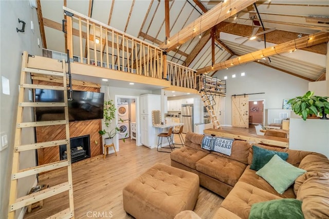 living room featuring stacked washing maching and dryer, high vaulted ceiling, a barn door, beamed ceiling, and light wood-type flooring