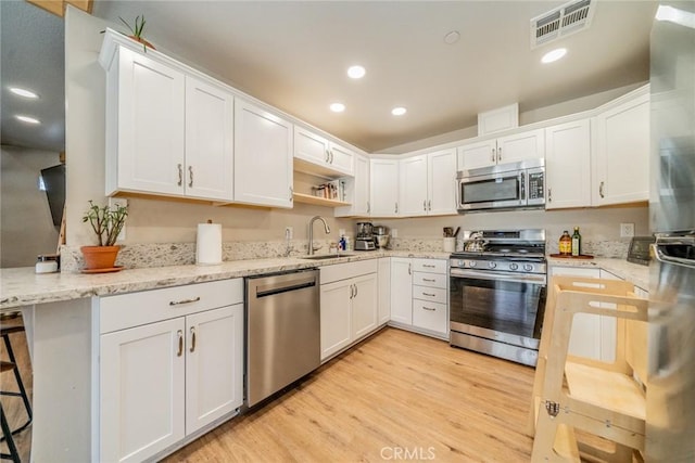 kitchen featuring appliances with stainless steel finishes, white cabinets, and kitchen peninsula