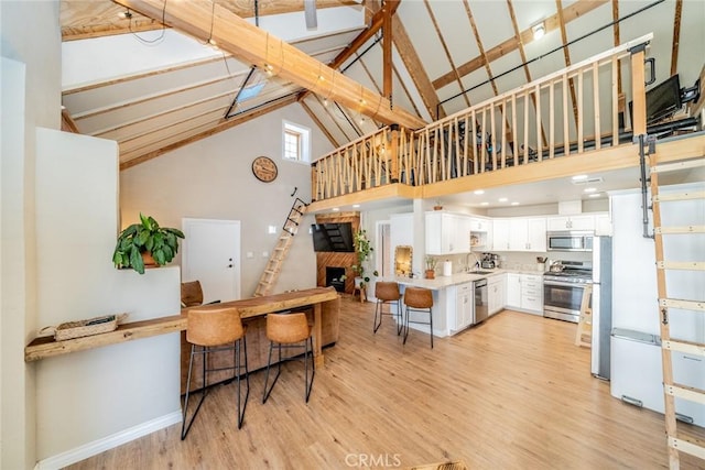 kitchen featuring high vaulted ceiling, beamed ceiling, stainless steel appliances, light hardwood / wood-style floors, and white cabinets