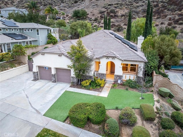 view of front of property with a garage, a front lawn, and solar panels