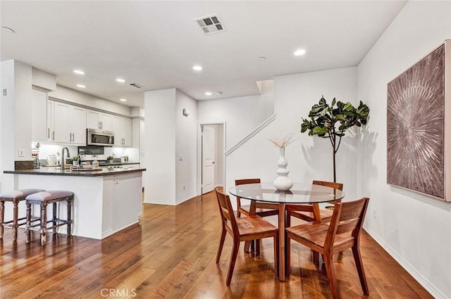 dining space with sink and wood-type flooring