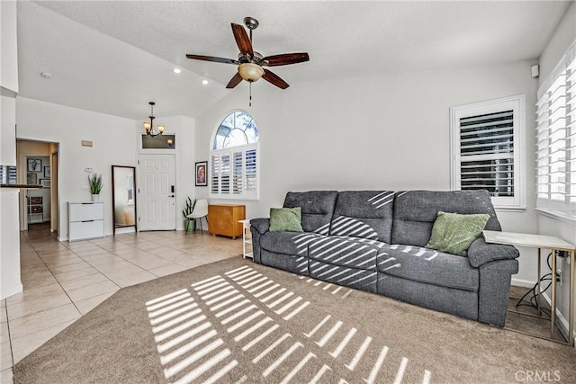 living room featuring light tile patterned flooring, lofted ceiling, and ceiling fan with notable chandelier