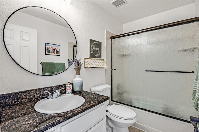 full bathroom with vanity, bath / shower combo with glass door, and toilet