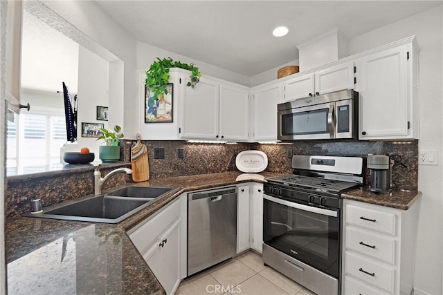 kitchen featuring sink, light tile patterned floors, white cabinetry, stainless steel appliances, and dark stone counters