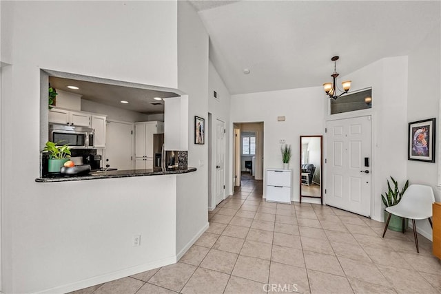 entryway with an inviting chandelier, high vaulted ceiling, and light tile patterned floors