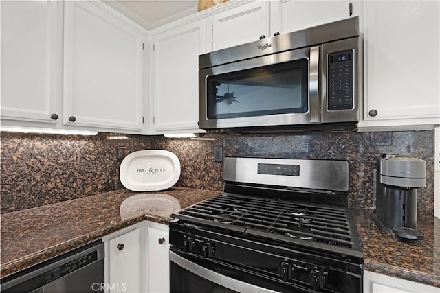 kitchen with backsplash, stainless steel appliances, dark stone counters, and white cabinets