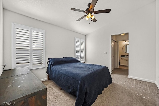 bedroom featuring ensuite bathroom, lofted ceiling, light colored carpet, and ceiling fan