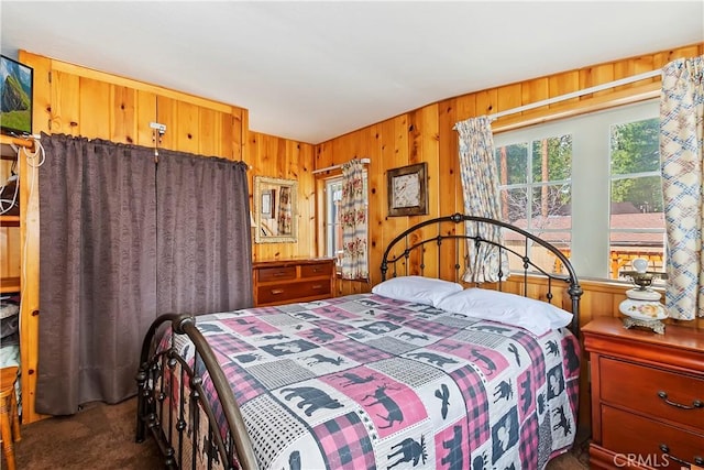 carpeted bedroom featuring wooden walls