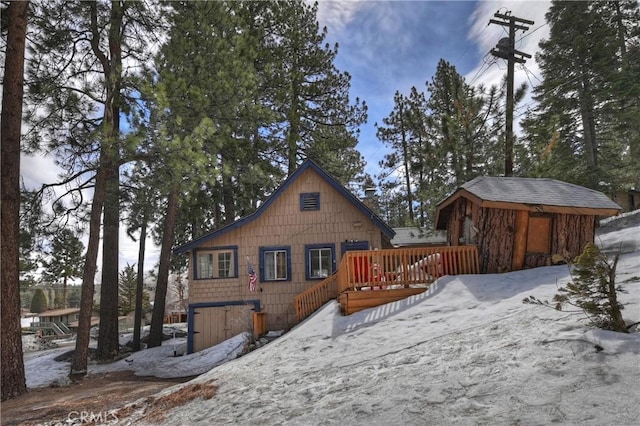 snow covered property featuring a shed and a deck