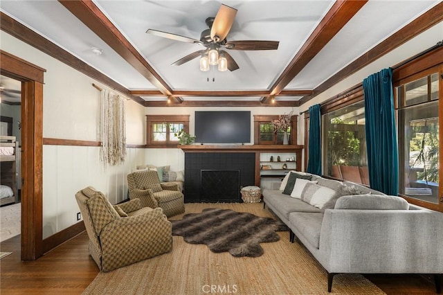 living room featuring hardwood / wood-style flooring, ceiling fan, beam ceiling, and a tiled fireplace