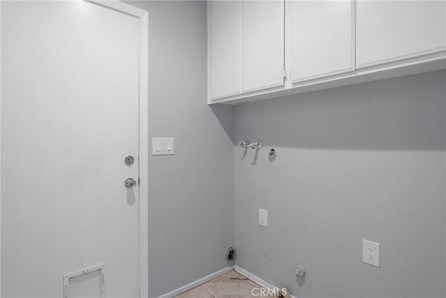 clothes washing area with gas dryer hookup, cabinets, and light tile patterned floors