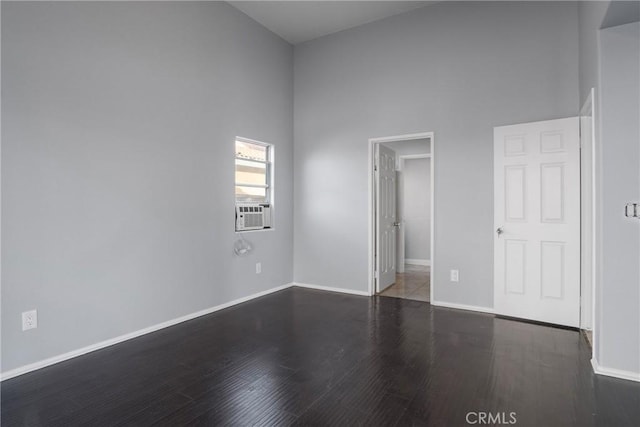 spare room with cooling unit, a towering ceiling, and dark hardwood / wood-style floors