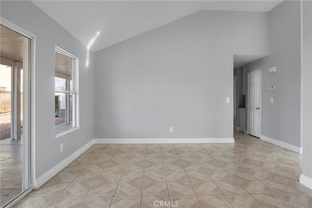 spare room with lofted ceiling and light tile patterned flooring