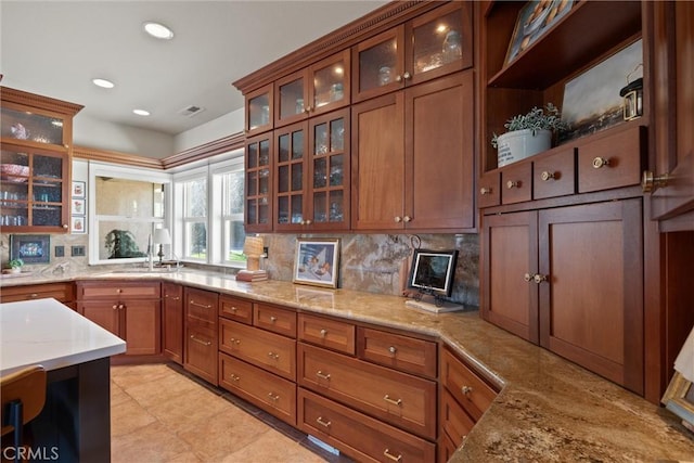 kitchen with tasteful backsplash, light stone countertops, sink, and light tile patterned floors