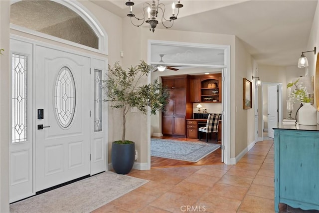 foyer with ceiling fan with notable chandelier and light tile patterned floors