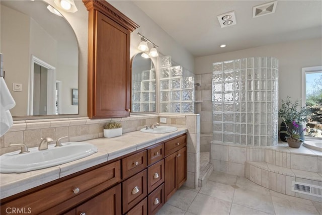 bathroom with a tile shower, vanity, tasteful backsplash, and tile patterned floors