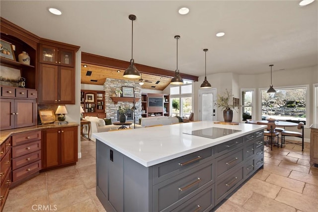 kitchen with black electric cooktop, pendant lighting, beamed ceiling, and a kitchen island