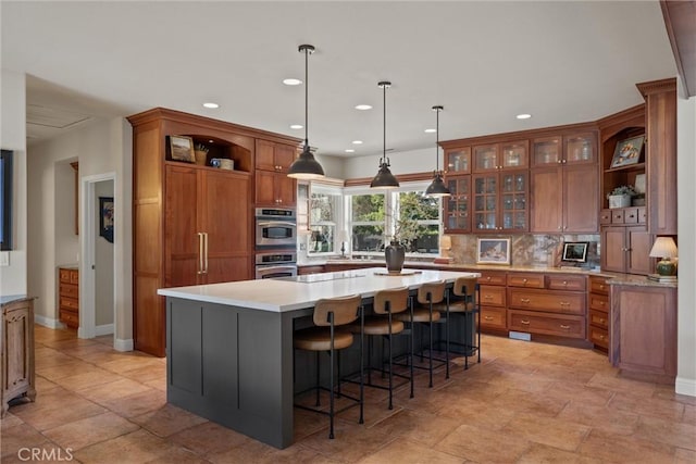 kitchen featuring pendant lighting, sink, backsplash, a kitchen breakfast bar, and a center island