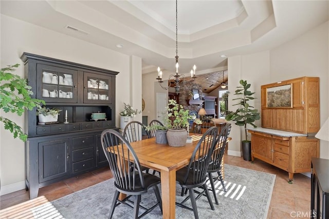 dining space featuring a raised ceiling, light tile patterned flooring, and a notable chandelier