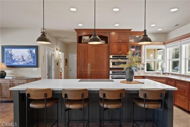 kitchen featuring a breakfast bar, stainless steel oven, and a center island with sink