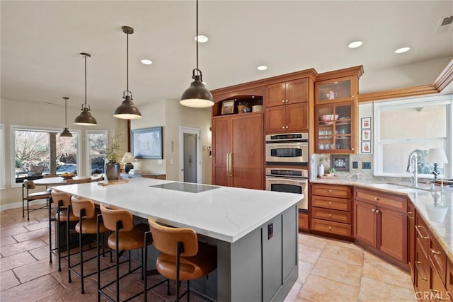 kitchen with pendant lighting, a breakfast bar area, a large island, light stone counters, and black electric cooktop