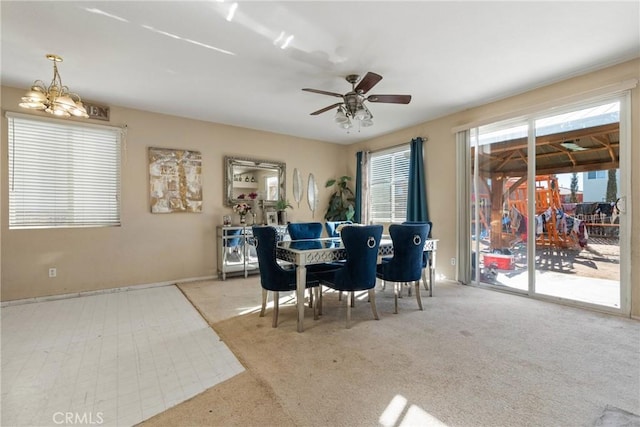 carpeted dining area featuring ceiling fan with notable chandelier