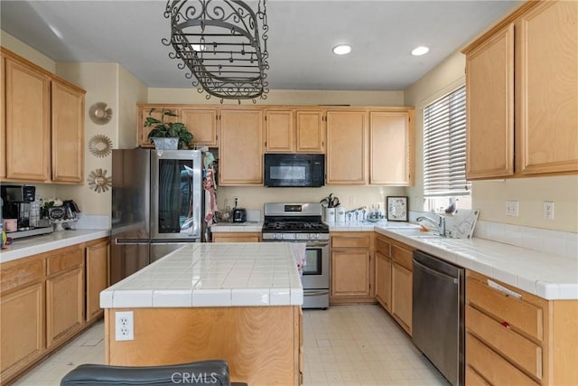 kitchen featuring tile countertops, light brown cabinets, a center island, and appliances with stainless steel finishes