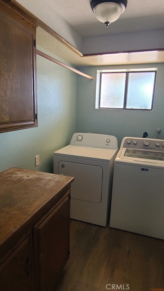 washroom featuring dark hardwood / wood-style floors, washing machine and dryer, and cabinets