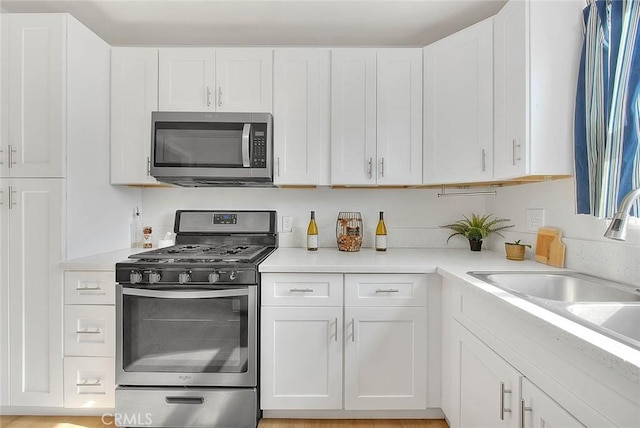 kitchen with appliances with stainless steel finishes, sink, and white cabinets