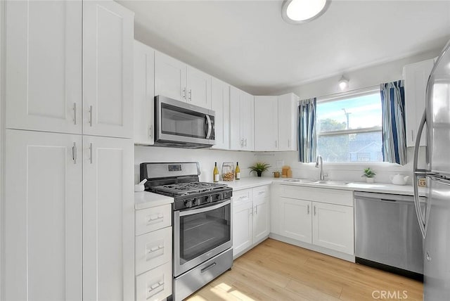 kitchen featuring white cabinetry, stainless steel appliances, sink, and light wood-type flooring