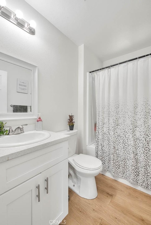 full bathroom with hardwood / wood-style flooring, shower / bathtub combination with curtain, vanity, and toilet