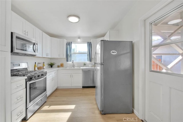 kitchen featuring white cabinetry, sink, light hardwood / wood-style flooring, and stainless steel appliances