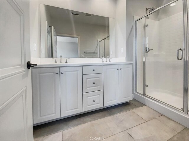 bathroom featuring tile patterned flooring, vanity, and a shower with shower door