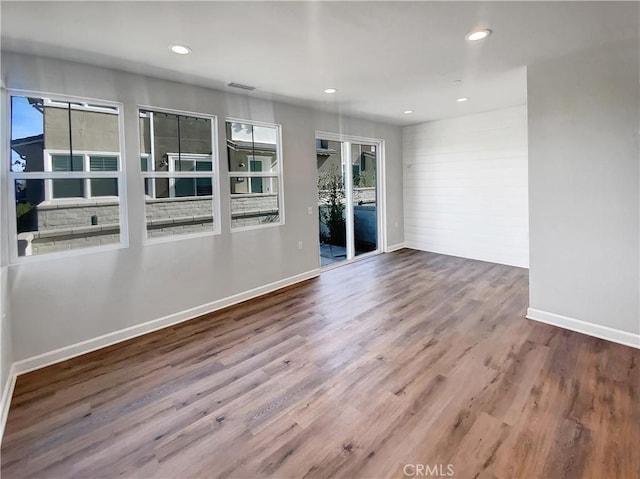 empty room with hardwood / wood-style flooring and a healthy amount of sunlight