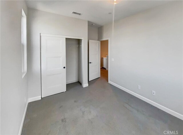 unfurnished bedroom featuring dark carpet and a closet