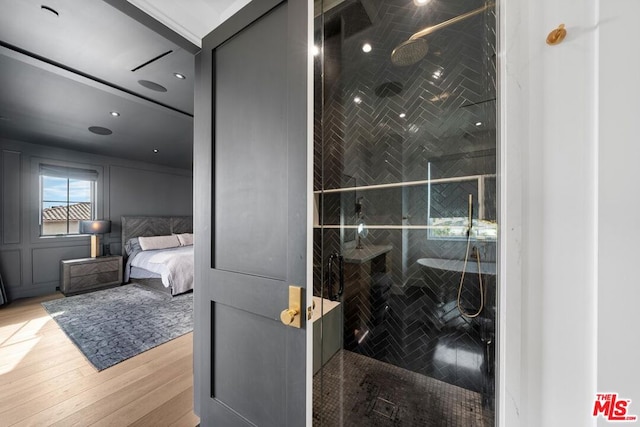 bathroom with a tile shower and wood-type flooring