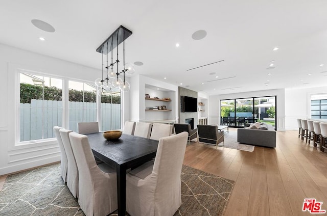 dining area with light wood-type flooring and built in shelves